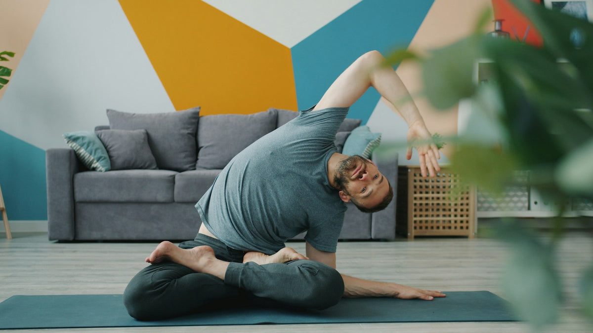 A man practicing yoga on a mat at home