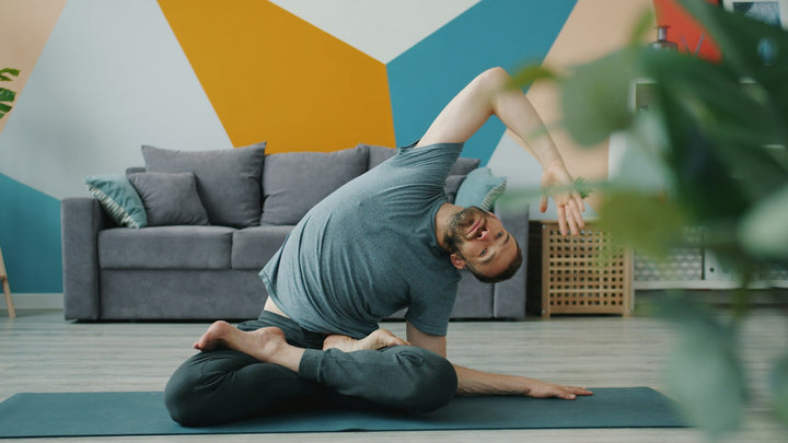A man practicing yoga on a mat at home